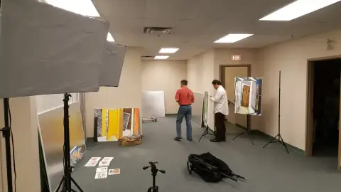 Team arranging artwork panels in an event space with lighting equipment