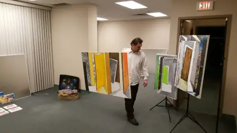 Artist positioning colorful door-themed paintings on stands