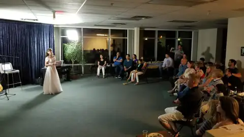 Audience seated watching a performer on stage during a recital