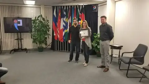 Instructor presenting a certificate to a smiling graduate with audience applauding